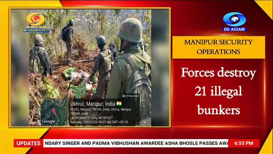 Soldiers in camouflage uniforms and helmets are clearing debris in a wooded area. They're working near what looks like makeshift shelters, their gear packed tightly.