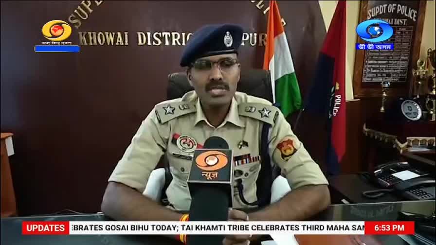 A man in a police uniform speaks into a microphone with the DD Arun Prabha logo. Behind him, the Indian flag and a police flag stand tall.