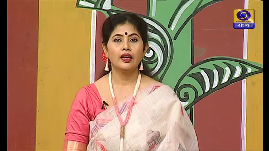 A woman in a sari speaks, her lips moving as she addresses the camera. The DD Bangla logo sits in the upper right corner, and a painted backdrop frames her.
