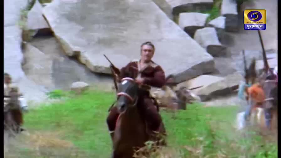 A man in a maroon outfit rides a horse toward me, holding a rifle. Behind him, other riders with spears follow, moving across the green field.
A man in a maroon outfit rides a horse toward me, holding a rifle. Behind him, other riders with spears follow, moving across the green field.
