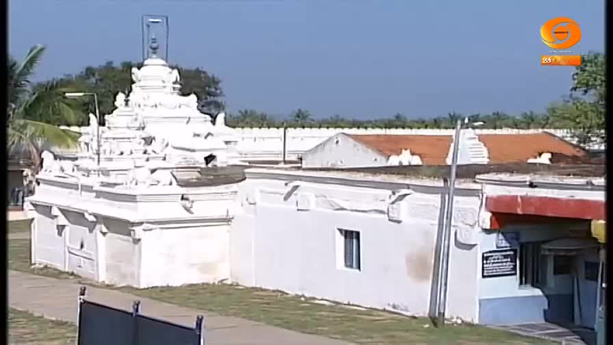 A white temple complex, with tiered structures and a small window, sits under a clear blue sky. The camera seems to be set up for a broadcast, perhaps for DD Chandana, with the logo visible in the corner.
