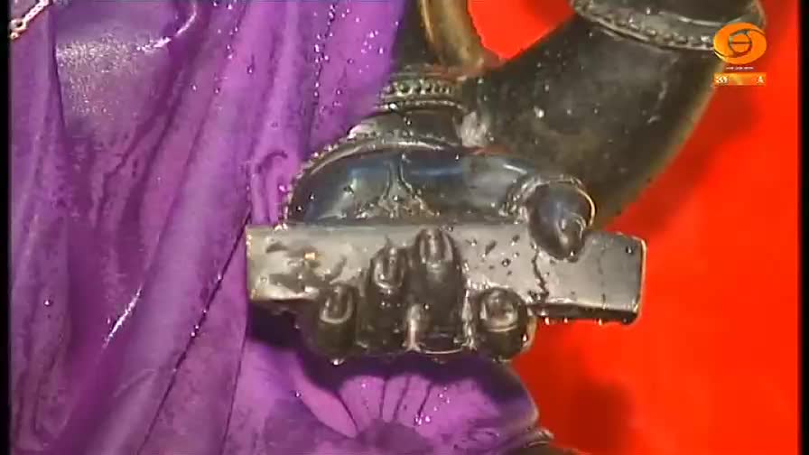 A dark hand, glistening with water, firmly grips a rectangular object. The purple fabric of a garment is visible, and the DD Chandana logo is in the corner.
