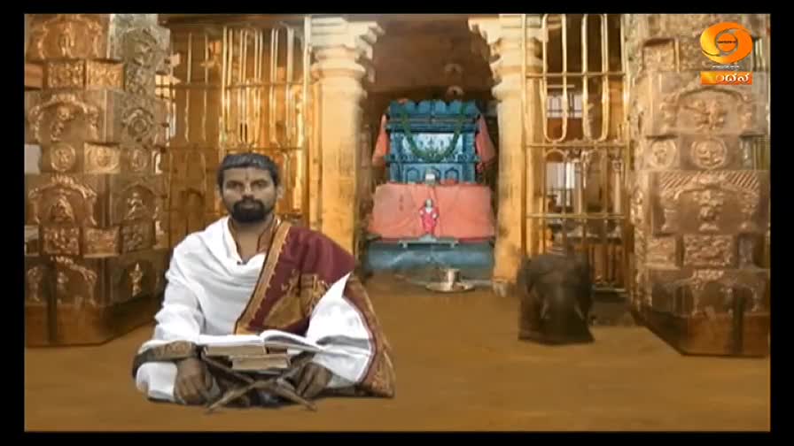 A man in white robes sits cross-legged, reading from a book, his gaze steady. Behind him, a decorated structure and ornate pillars frame the scene, perhaps a temple setting for a DD Chandana broadcast.
