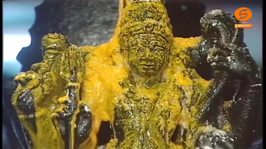 A statue, covered in a thick, yellow substance, is the focus of the shot. The figure's face, still visible, stares out from beneath the coating.
