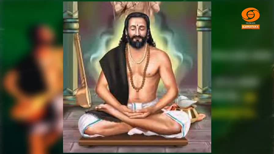 A man with a long beard sits in meditation, his hands resting gently in his lap. A tanpura leans against a pillar, and the DD Chandana logo is visible in the corner.
A man with a long beard sits in meditation, his hands resting gently in his lap. A tanpura leans against a pillar, and the DD Chandana logo is visible in the corner.