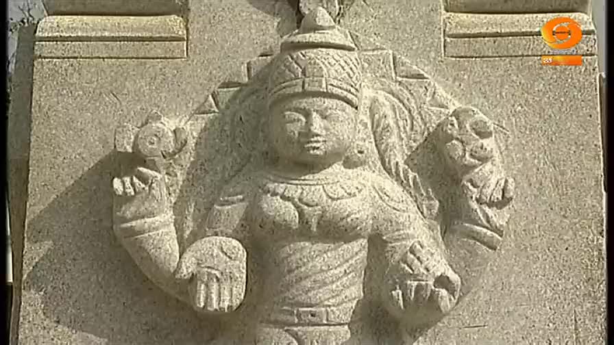 A stone carving of a figure, with a serene face and ornate headdress, is etched into a wall. The figure's arms are outstretched, and the hands hold objects that are difficult to make out.
A stone carving of a figure, with a serene face and ornate headdress, is etched into a wall. The figure's arms are outstretched, and the hands hold objects that are difficult to make out.
