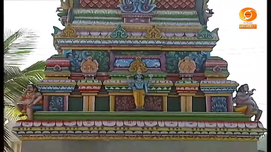 The brightly painted temple tower, likely from India, rises before me, adorned with intricate carvings and figures. A DD Chandana logo is visible in the corner, suggesting this might be a broadcast about the temple.
The brightly painted temple tower, likely from India, rises before me, adorned with intricate carvings and figures. A DD Chandana logo is visible in the corner, suggesting this might be a broadcast about the temple.