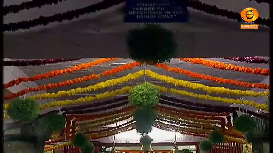 Garlands of bright flowers hang from the ceiling, their colors a vibrant contrast against the white backdrop. Below, a sign reminds visitors to place offerings in the hundi.
Garlands of bright flowers hang from the ceiling, their colors a vibrant contrast against the white backdrop. Below, a sign reminds visitors to place offerings in the hundi.