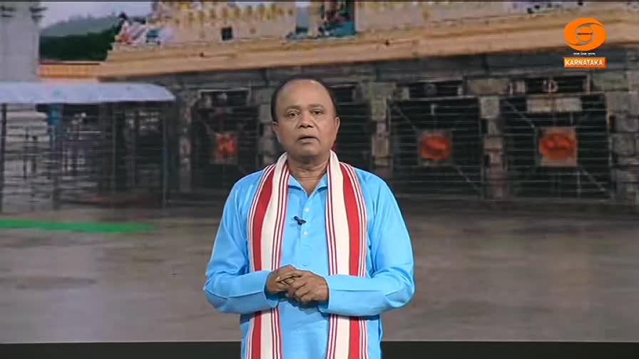 A man in a light blue kurta stands before a backdrop of a temple, his hands clasped in front of him. He wears a scarf with red and white stripes, likely a DD Chandana broadcast from India.
A man in a light blue kurta stands before a backdrop of a temple, his hands clasped in front of him. He wears a scarf with red and white stripes, likely a DD Chandana broadcast from India.