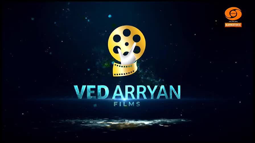 The "VED ARRYAN FILMS" logo appears against a dark, starry background. A golden film reel spins above the text, with the DD Chandana Karnataka logo in the top right corner.