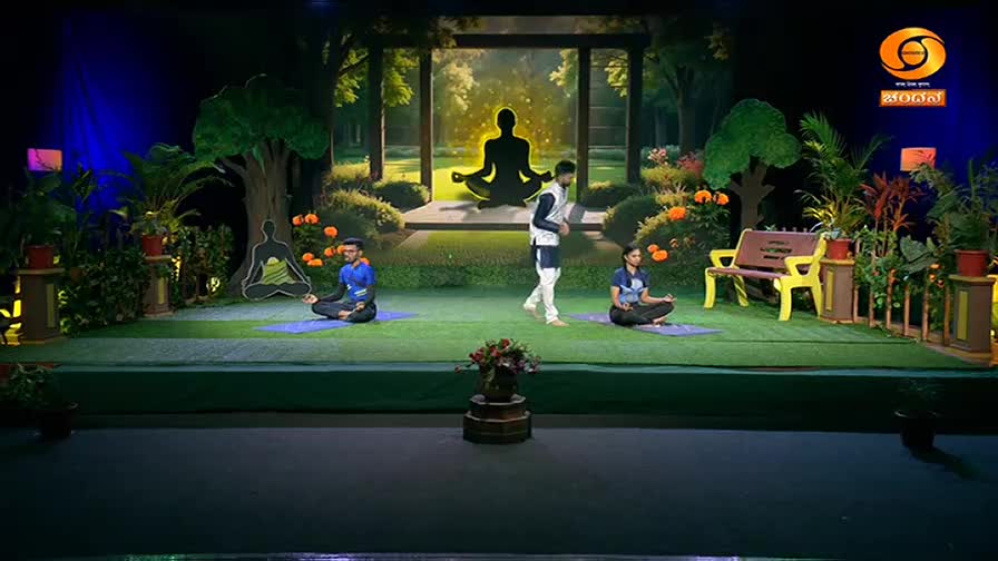 Two people sit in meditation on yoga mats, while another walks between them on a set designed to look like a park. The DD Chandana logo is visible in the top right corner.