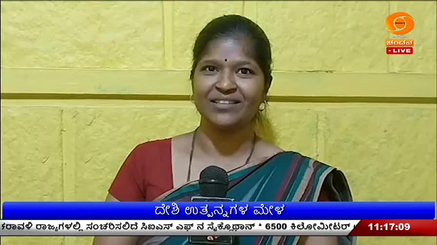 A woman stands before a microphone, her sari a mix of teal and red. The DD Chandana logo appears in the upper right corner, indicating a live broadcast from India.