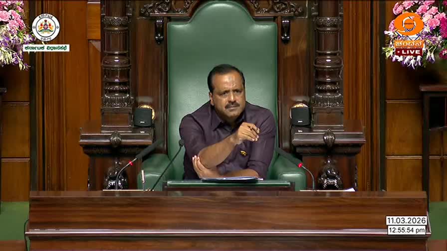 A man sits in a large, green chair, gesturing with his right hand as he speaks. The DD Chandana logo is visible in the corner, indicating this is a live broadcast from India.