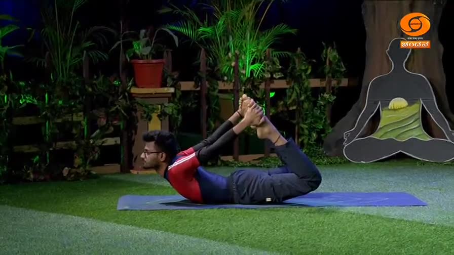 A man holds a yoga pose, arching his back and grasping his ankles. The DD Chandana logo is visible in the background.