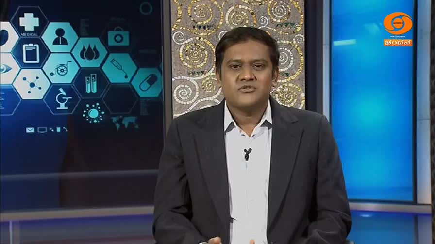 A man in a dark suit stands before a screen displaying medical icons. The DD Chandana logo appears in the corner of the screen.