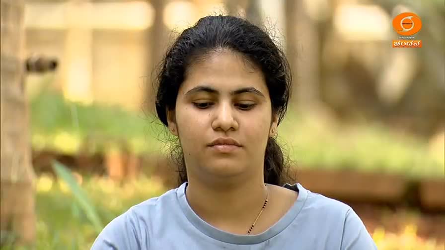A young woman with dark hair looks down, her expression thoughtful. The DD Chandana logo is visible in the background.