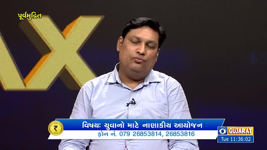 A man in a light blue shirt is speaking, his expression thoughtful. Below him, a chyron from DD Girnar, Gujarat, displays the topic and phone numbers.
