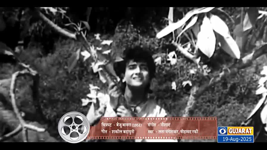 A man with dark, curly hair smiles up towards the light, surrounded by foliage. The scene is a clip from the 1952 film *Baiju Bawra*, broadcast on DD Girnar.
