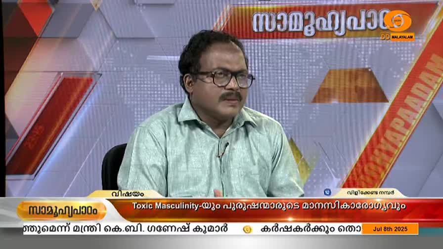 A man in glasses and a light green shirt sits at a desk, speaking on a DD Malayalam news program. The topic, "Toxic Masculinity," is displayed in Malayalam and English on the lower third of the screen.
