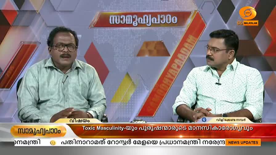 Two men in shirts sit at a table, facing the camera on a DD Malayalam set. The lower third banner displays a discussion about "Toxic Masculinity" and "Mental Health."
