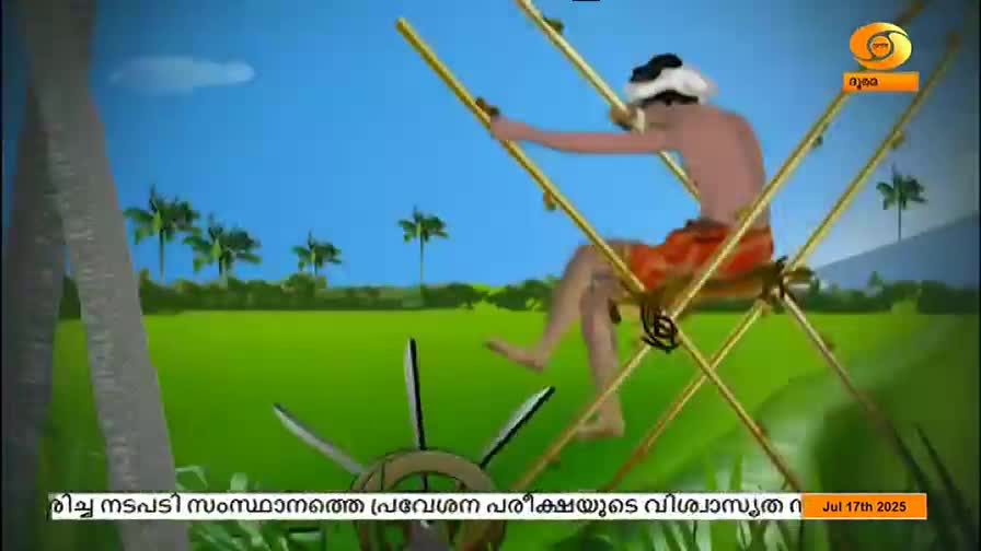A man, wearing a head covering and orange shorts, sits on a wooden frame, seemingly operating a water wheel. The scene, likely from DD Malayalam, is set in a vibrant green field under a bright blue sky.
