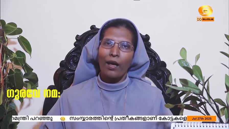 A woman in a habit speaks directly to the camera, her mouth moving as she talks. The DD Malayalam logo is visible in the corner, and text scrolls across the bottom of the screen.
