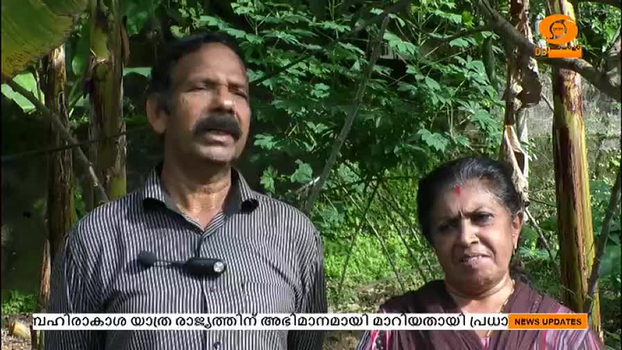 A man and woman stand before a backdrop of greenery, speaking into a microphone. The DD Malayalam logo and news updates are visible in the lower right corner. 
