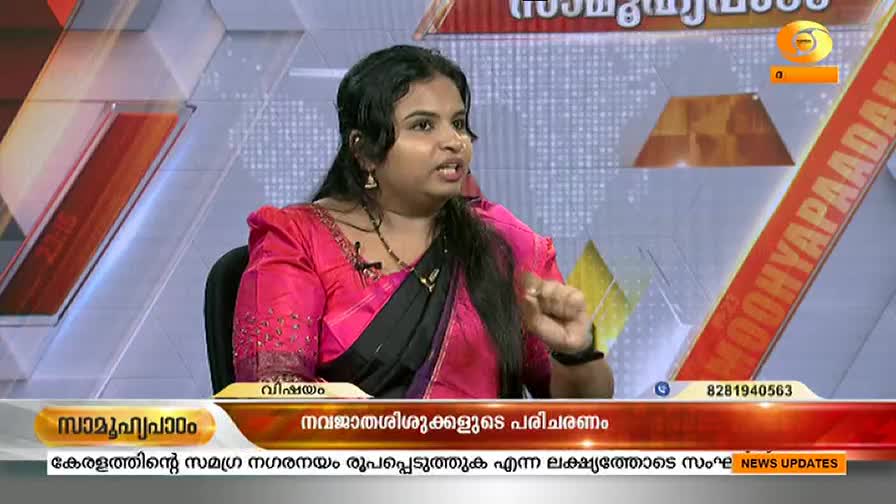 A woman in a pink sari gestures emphatically, speaking into a microphone on a DD Malayalam news program. The lower third of the screen displays text in Malayalam, with a phone number visible at the bottom.
