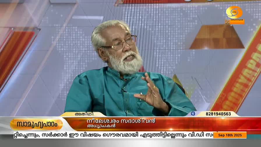 A man with a long white beard and glasses gestures with his right hand while speaking on DD Malayalam. Below, the name of the guest and the program title are displayed on a lower third.

