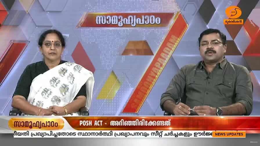 Two people sit at a desk, facing forward on a DD Malayalam set. A graphic about the POSH Act is displayed on the screen behind them.
