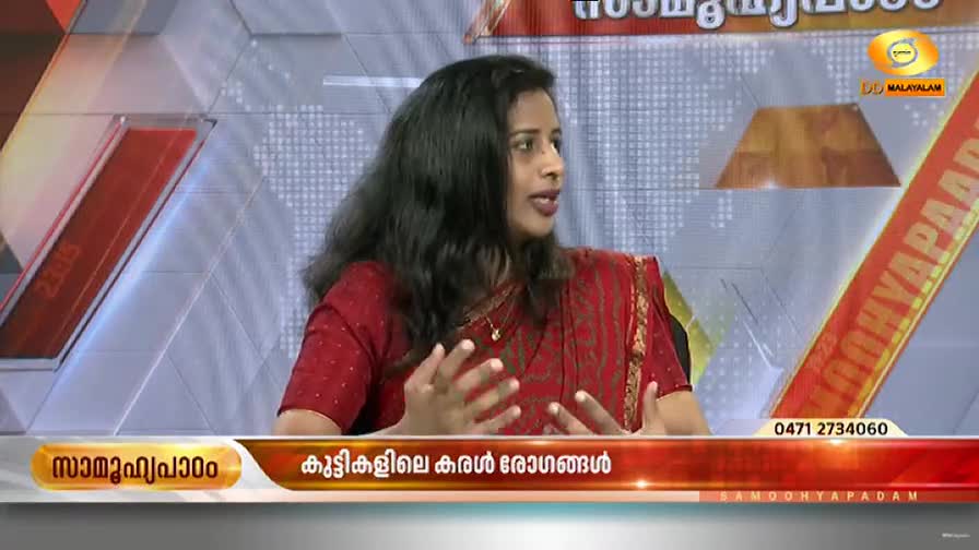 A woman in a red sari gestures with her hands as she speaks on a DD Malayalam program. The screen displays text in Malayalam, with a phone number and the DD Malayalam logo visible.
A woman in a red sari gestures with her hands as she speaks on a DD Malayalam program. The screen displays text in Malayalam, with a phone number and the DD Malayalam logo visible.