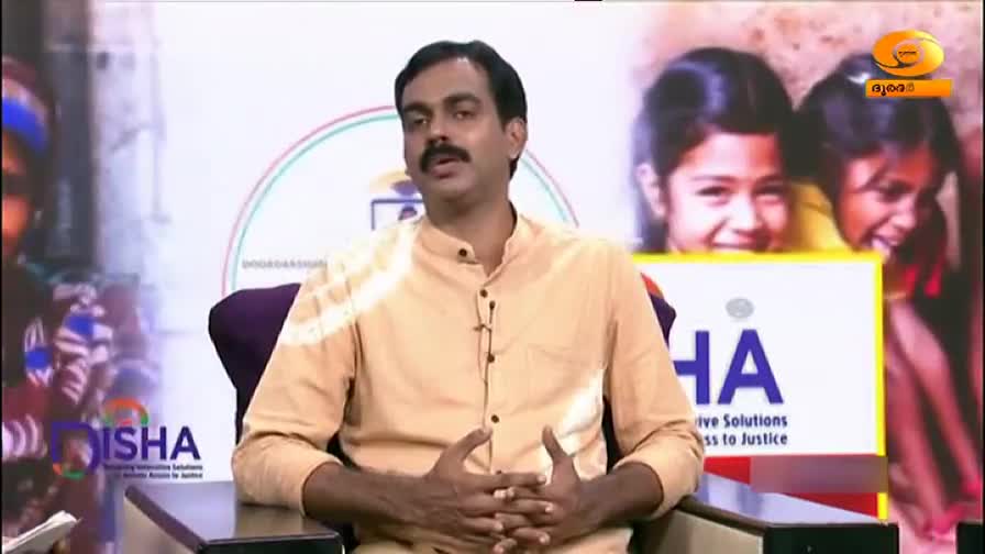 A man in a light-colored shirt sits in a studio, speaking with his hands. Behind him, a screen displays images of children and a logo for "Disha."
A man in a light-colored shirt sits in a studio, speaking with his hands. Behind him, a screen displays images of children and a logo for "Disha."