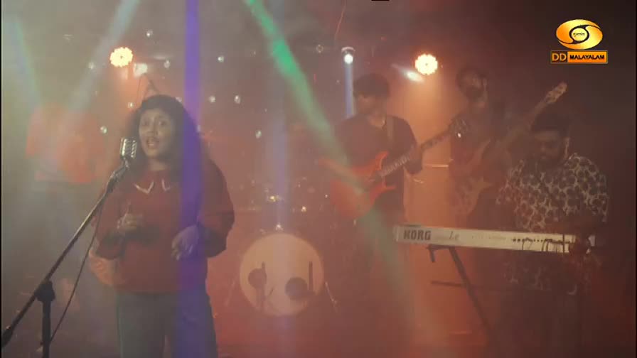 A woman sings into a vintage microphone, her voice cutting through the smoky stage lights. Behind her, a band plays, with guitars and a keyboard filling out the sound.