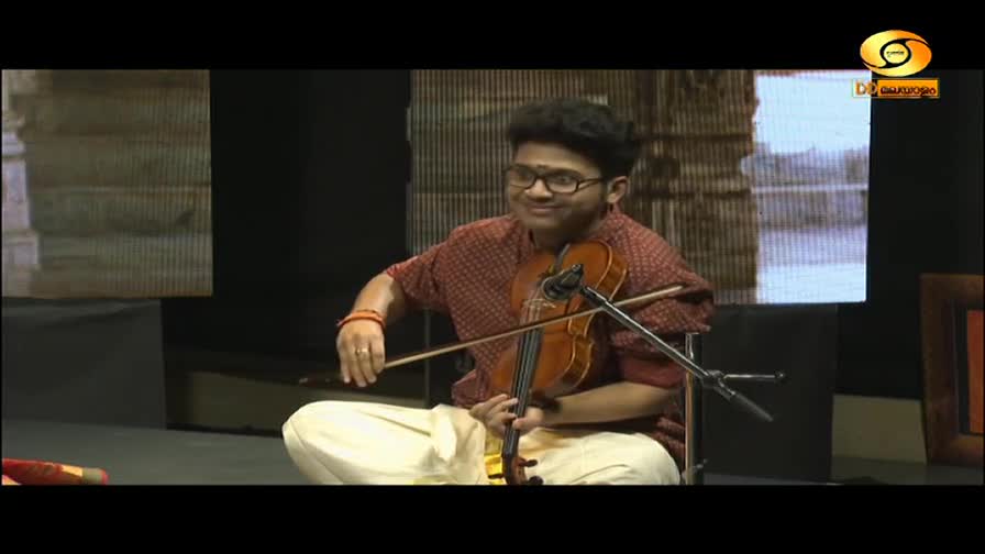 A young man in traditional Indian attire plays the violin, his bow gliding across the strings. The DD Malayalam logo is visible in the corner. A young man in traditional Indian attire plays the violin, his bow gliding across the strings. The DD Malayalam logo is visible in the corner.