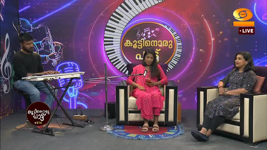 A man plays a keyboard while a woman in a pink outfit looks at her phone. Another woman sits to her right, smiling. The DD Malayalam logo is visible in the corner.
