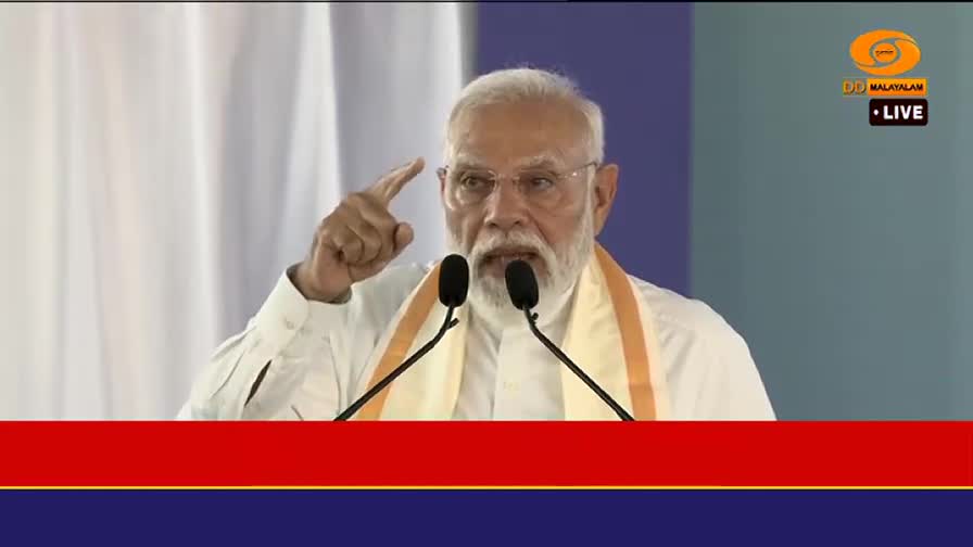 The Prime Minister speaks into two microphones, his right hand raised with a finger pointing skyward. A DD Malayalam LIVE banner is visible in the upper right corner.