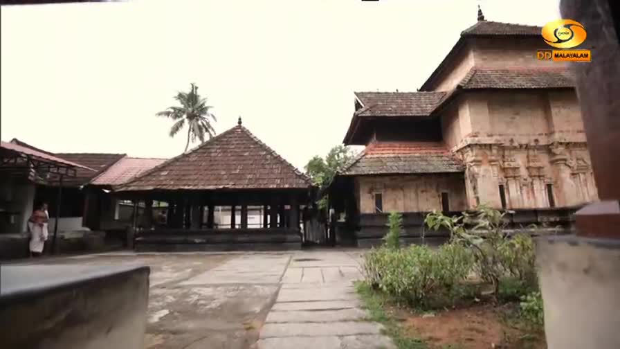 A woman in a white sari walks across the courtyard of a temple complex. The DD Malayalam logo is visible in the upper right corner. A woman in a white sari walks across the courtyard of a temple complex. The DD Malayalam logo is visible in the upper right corner.