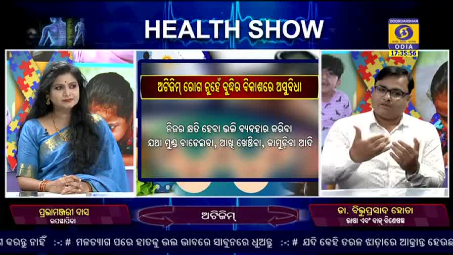 A woman in a blue sari sits and looks towards the camera, while a man in glasses gestures with his hands as he speaks. The DD Odia "Health Show" is discussing autism.

