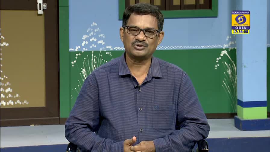 A man in glasses speaks directly to the camera, his hands clasped in front of him. The DD Odia logo and the time are visible on the wall behind him.
