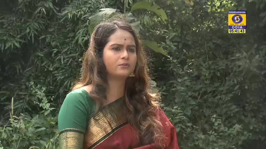 A woman in a green and red sari speaks, her eyes focused off-camera. The DD Odia logo and time display in the corner, suggesting a broadcast from India.
