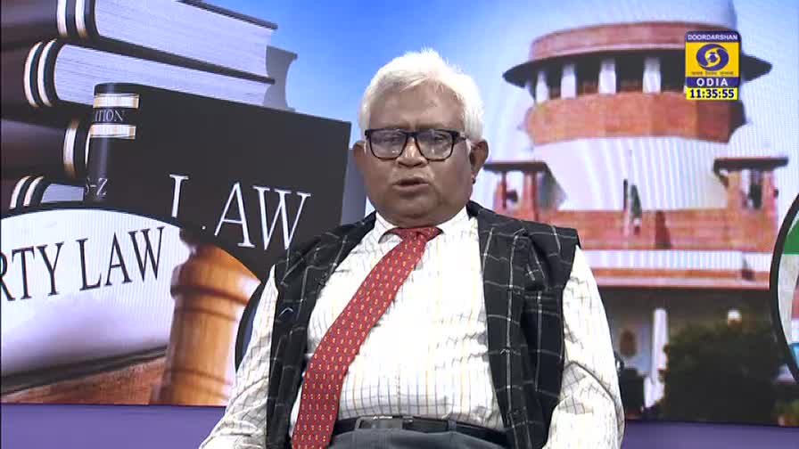 The man in glasses, wearing a patterned vest over a white shirt and red tie, is speaking directly to the camera on DD Odia. Behind him, a backdrop shows the Supreme Court building and a stack of law books.

