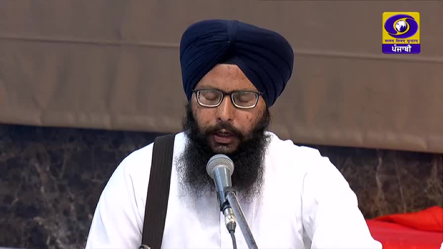 A man in a turban and glasses speaks into a microphone, his beard framing his face. The DD Punjabi logo is visible in the corner, indicating a broadcast from India.
