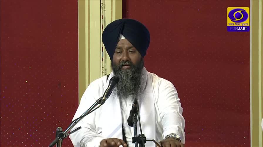 A man in a turban and white shirt speaks into a microphone, his words broadcast on DD Punjabi. The logo of the Indian television channel is visible in the corner.

