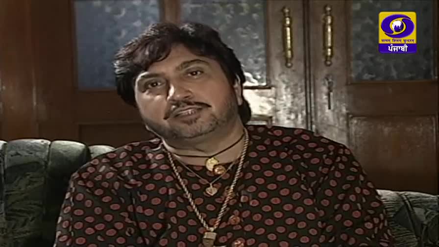 The man in the polka-dot shirt is speaking, his face lit by the soft studio lights. A logo for DD Punjabi is visible in the corner.
