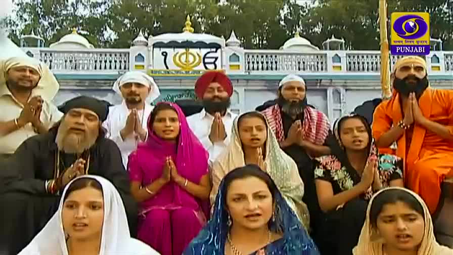 A group of people, dressed in various religious garments, stand with their hands clasped in front of them. The DD Punjabi logo sits in the corner, and they appear to be outside a temple.
