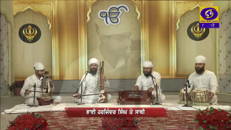 Four men in white robes and turbans sit on a stage, playing instruments and singing into microphones. The broadcast is from DD Punjabi, with the logo visible in the top right corner.

