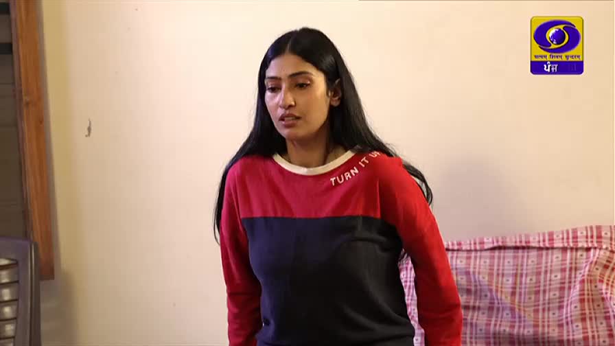 The woman in the red, navy, and black sweatshirt is looking slightly off-camera. A DD Punjabi logo is in the background.
