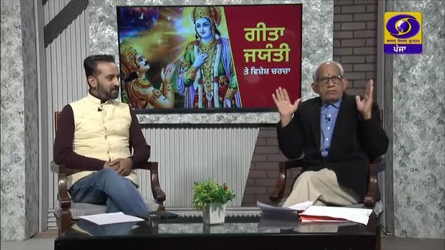 An older man in a black blazer gestures with both hands as he speaks. The DD Punjabi logo is visible, and the backdrop features an image of a deity and text in Punjabi.
