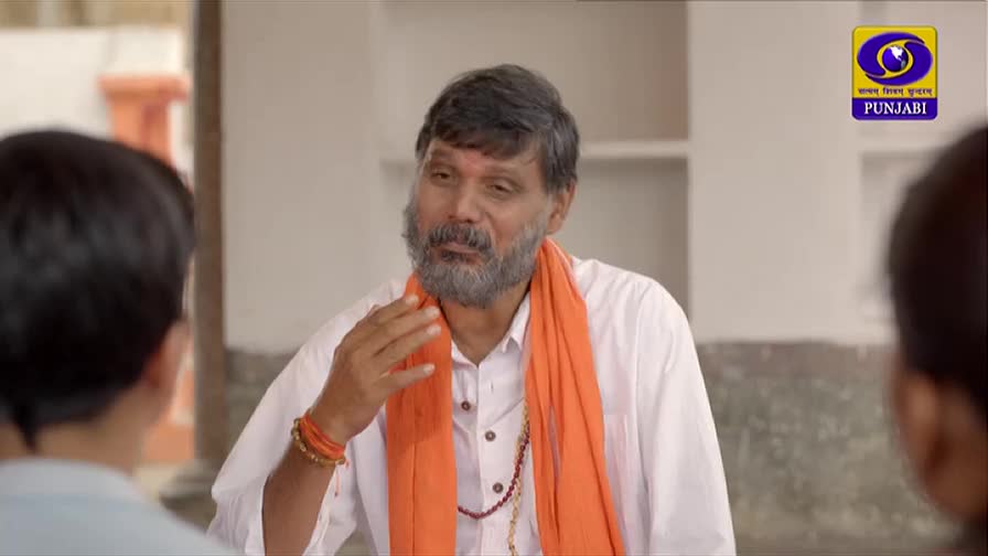 A man in a white shirt and orange scarf gestures with his hand, speaking to two children. The DD Punjabi logo is visible in the corner.