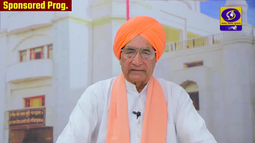 A man in a bright orange turban and scarf speaks directly to the camera. The DD Punjabi logo is visible in the background, indicating a broadcast from India.